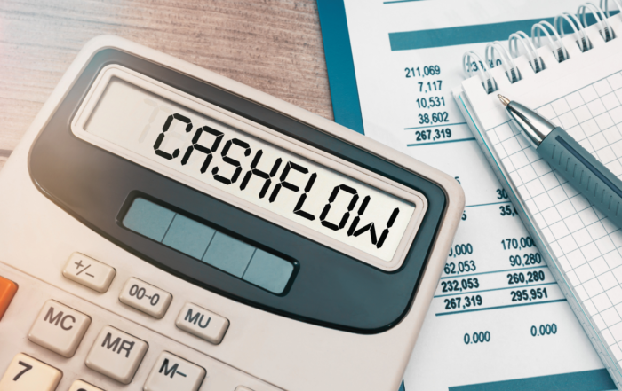 Image of a calculator reading "CASHFLOW" and writing implements to help businesses with SaaS budgeting.