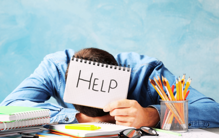 CEO has head on desk out of frustration and is holding a 'help' sign. Struggling with SaaS Finance is a common theme in many SaaS ventures.