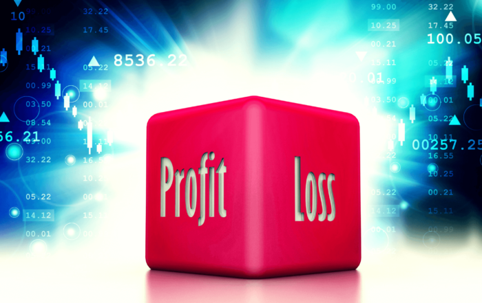 Pink dice that says 'profit' and 'loss' in front of a dark background with financial numbers and charts.